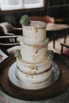 a three tiered white cake with succulents on the top and bottom