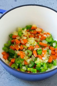 chopped carrots, celery and onions in a blue pot on a table