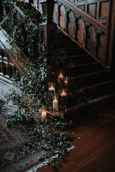 candles and greenery on the ground in front of an old staircase with wooden railings