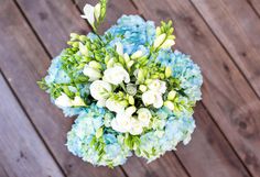 a bouquet of blue and white flowers sitting on top of a wooden floor