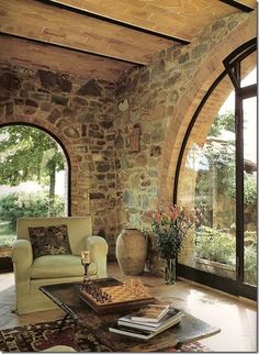 a living room filled with furniture next to an arched glass door and window overlooking a lush green field