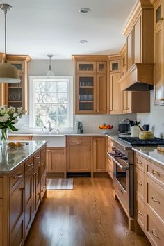 a kitchen filled with lots of wooden cabinets and counter top space next to a window