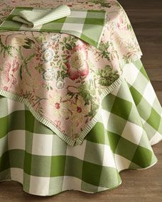 a green and white checkered table cloth with flowers on it, sitting on a wooden floor