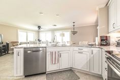 a large kitchen with white cabinets and stainless steel dishwasher, stove top oven and microwave