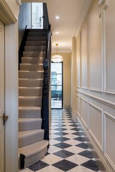 a hallway with stairs and black and white checkerboard flooring on the walls