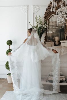 a woman in a white wedding dress is holding her veil