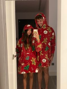 a man and woman wearing matching christmas pajamas taking a selfie in the bathroom mirror