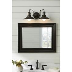 a bathroom sink sitting under a mirror next to a wall mounted faucet with two lights on it