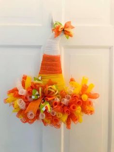 an orange and yellow wreath hanging on the front door with ribbons attached to it's sides