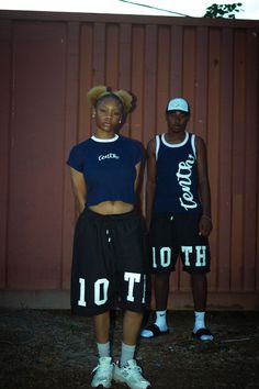 two people standing next to each other in front of a red wall with the word hot on it