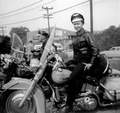 black and white photograph of two people on motorcycles with one person sitting on the motorcycle