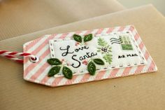 a small tag that says love santa and has green leaves on it with red and white stripes