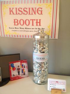 a glass jar filled with lots of candy next to a sign that says kissing booth