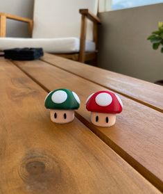 two small mushroom figurines sitting on top of a wooden table next to each other