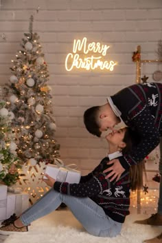 a couple kissing in front of a christmas tree