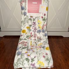 a white chair with flowers on it sitting in front of a wooden floor next to a door