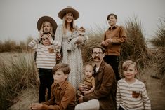 a group of people sitting on top of a beach next to tall grass and sand