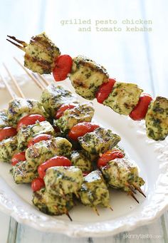 a white plate topped with chicken and tomato kabobs