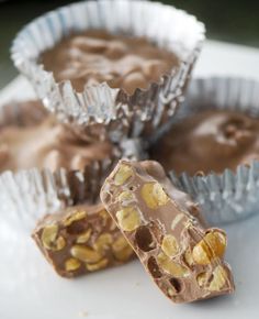 three pieces of chocolate with nuts in them on a white plate next to foil cups