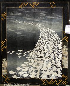 a black and white quilt with birds flying in the sky on it's sides