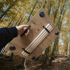 a person is holding a wooden board with several sticks in it and an arrow on the back