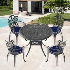 an outdoor table with four chairs next to a swimming pool