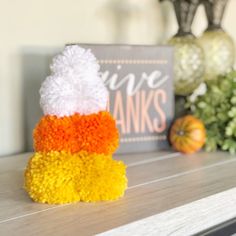 a knitted hat sitting on top of a wooden table next to a sign and flowers