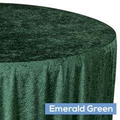 the emerald green tablecloth is draped over an empty round table with a blue sign that reads emerald green