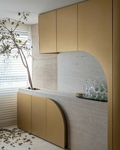 a kitchen with marble counter tops and wooden cabinetry next to a tree in the corner