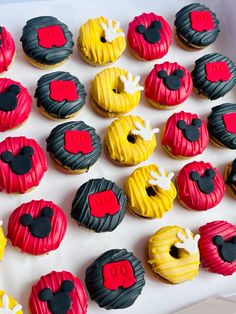 mickey mouse cupcakes are arranged on a white tray with red, yellow and black frosting