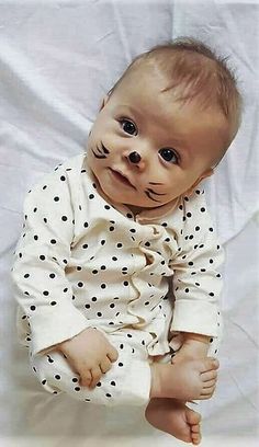 a baby with fake teeth sitting on a white sheet