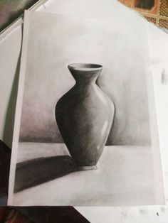 a drawing of a vase sitting on top of a table next to a piece of paper