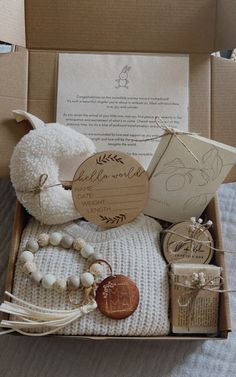 an open box with various items in it sitting on a bed next to a card