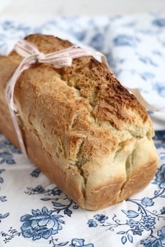 a loaf of bread wrapped in a ribbon on a blue and white tablecloth with flowers