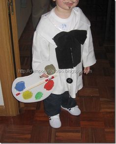 a little boy dressed up as a cow holding a paintbrush and an acrylic palette