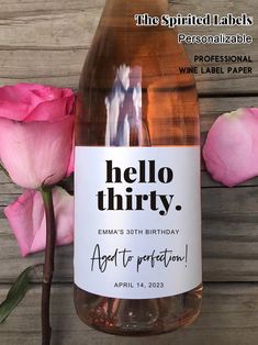 a bottle of wine that is next to some pink roses and a wooden background with the words hello thirty written on it