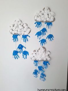 blue and white handprinted clouds are hanging from the side of a wall with elephants painted on them