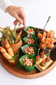 a tray filled with different types of food on top of a white table next to a person's hand