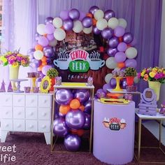 there is a purple and white party with balloons on the table, flowers in vases