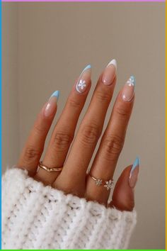 a woman's hand with blue and white manicures on it, wearing a sweater