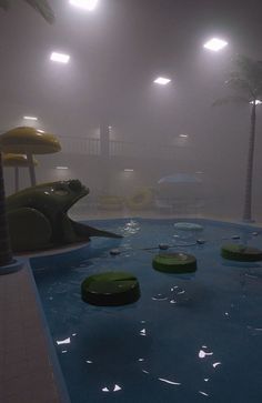 an indoor pool with water slides and palm trees in the foggy night time sky