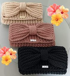 three knitted headbands with bows and flowers on the table next to each other