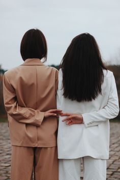 two people standing next to each other on a brick road