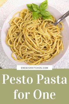 pesto pasta with basil on top in a white bowl and the title overlay reads pesto pasta for one