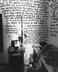 black and white photograph of a bedroom with writing on the wall