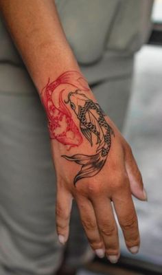 a woman's hand with a dragon tattoo on her left wrist and red ink