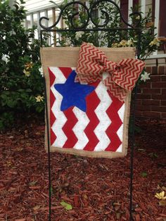 a red, white and blue quilt hanging on a wrought iron fence with a bow