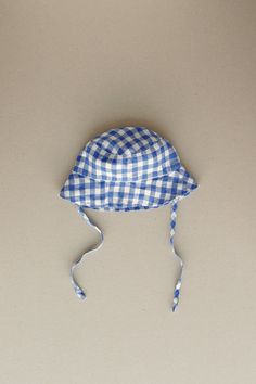 Product photos - blue gingham. Our baby bucket hat will help to stay protected and keep it cute. Tailored to shade the face and ears along with side ties to keep the hat secure. A classy and comfortable choice for any forecast. Lightweight, cozy and charming. This baby bucket hat is designed to be comfortably loose-fitting and allow for growth as the baby grows. Pre-tied Cotton Hat For Beach, Adjustable Bucket Hat For Picnic, Adjustable Brimmed Bucket Hat For Picnic, Cute Blue Sun Hat For Summer, Cute Blue Bucket Hat For Summer, Cute Blue Summer Sun Hat, Cute Blue Summer Bucket Hat, Summer Cotton Hat For Picnic, Summer Cotton Hat For Picnics