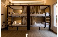 bunk beds in a room with wooden flooring and curtains on the windowsills