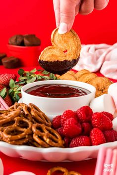 a person dipping some kind of pastry into a bowl with raspberries on the side